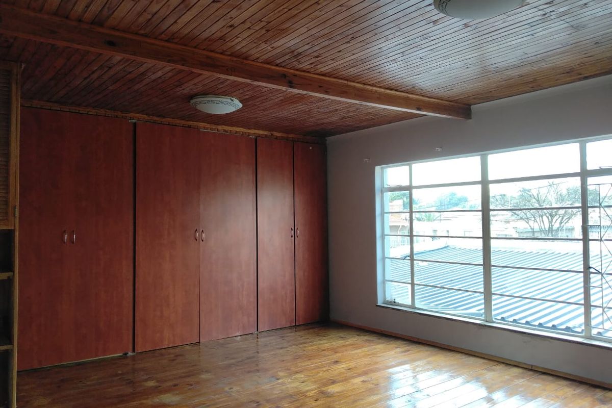 Spacious bedroom featuring timber ceiling, polished timber flooring, and extensive built-in cupboard storage with large windows providing natural light.