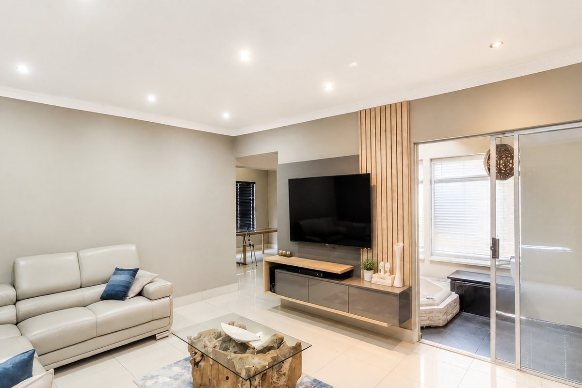Modern living room featuring a sleek floating media console, decorative slatted timber wall paneling, recessed downlights, and large sliding glass doors leading to an adjacent space.
