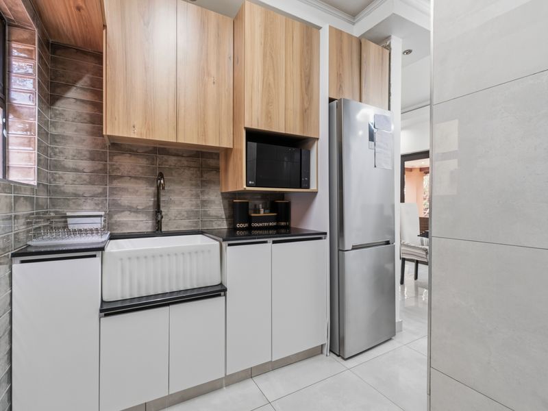 Modern scullery featuring wood-finish cabinetry, a farmhouse sink, stone countertops, and a tiled backsplash, providing a functional and stylish prep area.