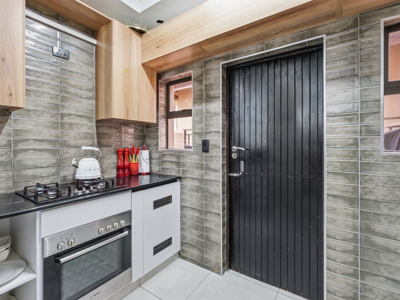 Modern kitchen featuring sleek cabinetry, subway tile backsplash, gas hob, built-in oven, and a skylight for natural illumination.
