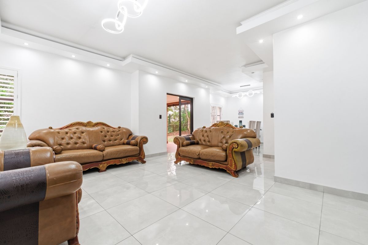 Spacious living room featuring polished porcelain floor tiles, recessed ceiling lighting, and a sliding glass door providing access to the outdoor area.