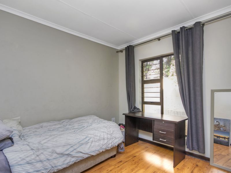 A bedroom featuring timber flooring, a louvered window with a curtain rod, and coved ceiling detailing.