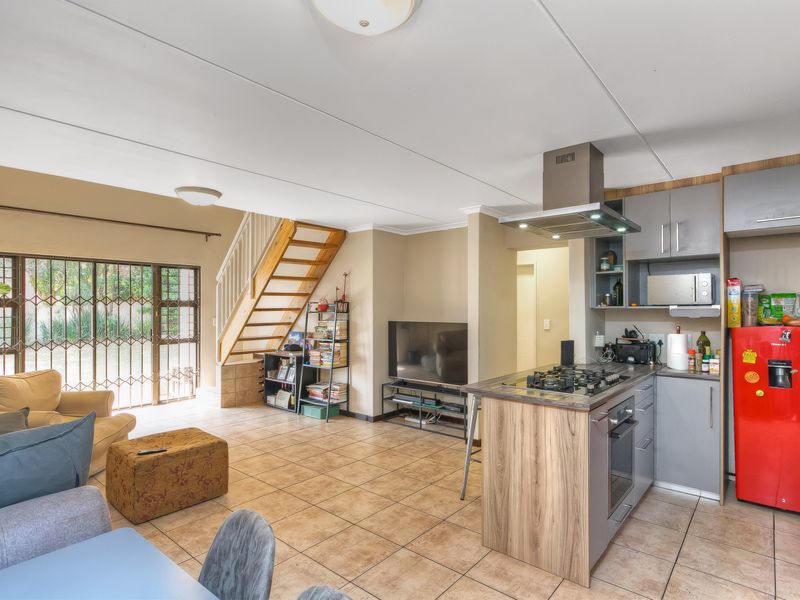 Open-plan living area featuring a modern kitchen with built-in appliances, tiled flooring, and a staircase leading to the upper level.