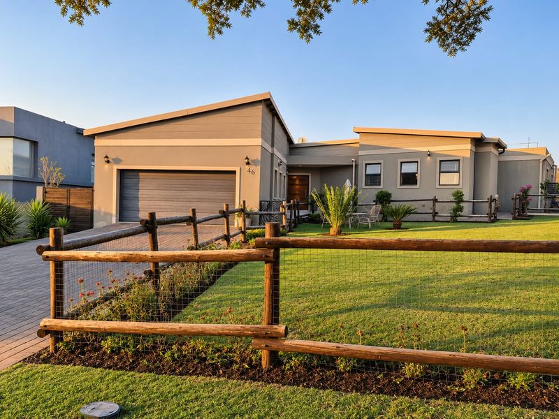 A well-maintained modern single-story house featuring a paved driveway, integrated garage, and a neat front lawn enclosed by a timber fence.