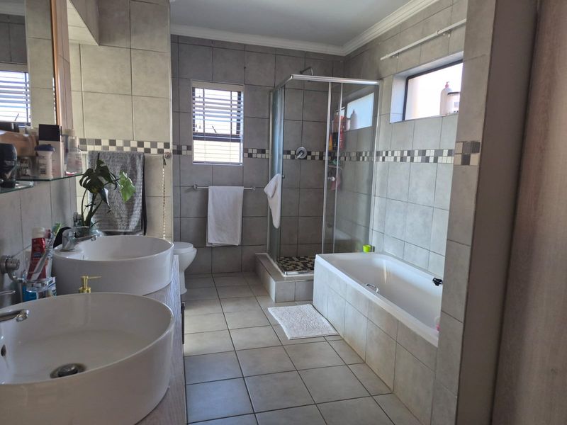 A well-appointed bathroom featuring a double vanity with vessel sinks, a separate shower enclosure, and a built-in bathtub with neutral tiled finishes.