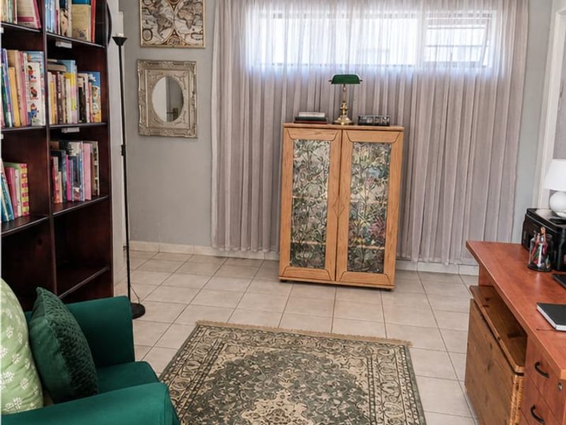 A well-maintained home office featuring neutral wall tones, tiled flooring, recessed downlighting, and decorative cornicing.