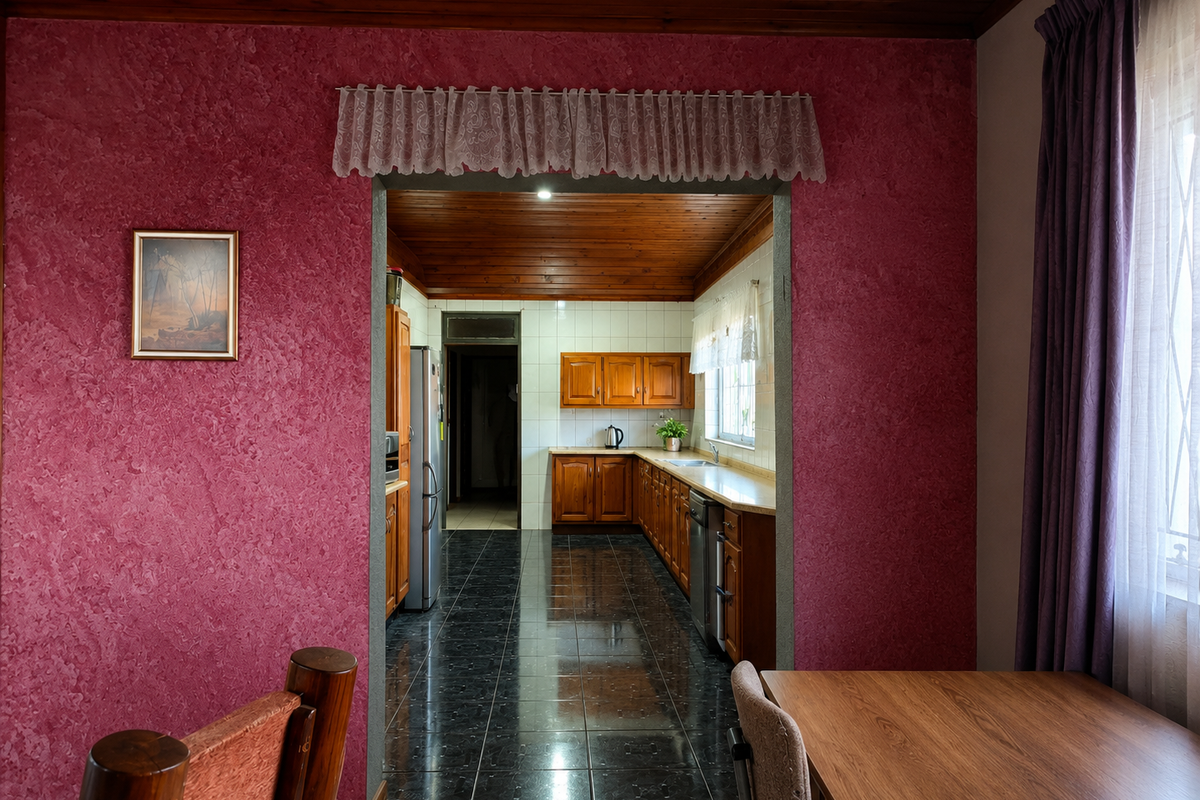 A functional kitchen featuring wooden cabinetry, tiled flooring, and a tiled backsplash, connected to an adjacent living area with a distinct textured wall finish.