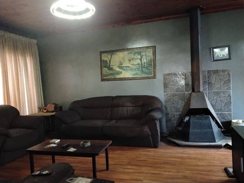 Living room featuring a prominent freestanding fireplace with stone surround, timber ceiling, and laminate flooring.