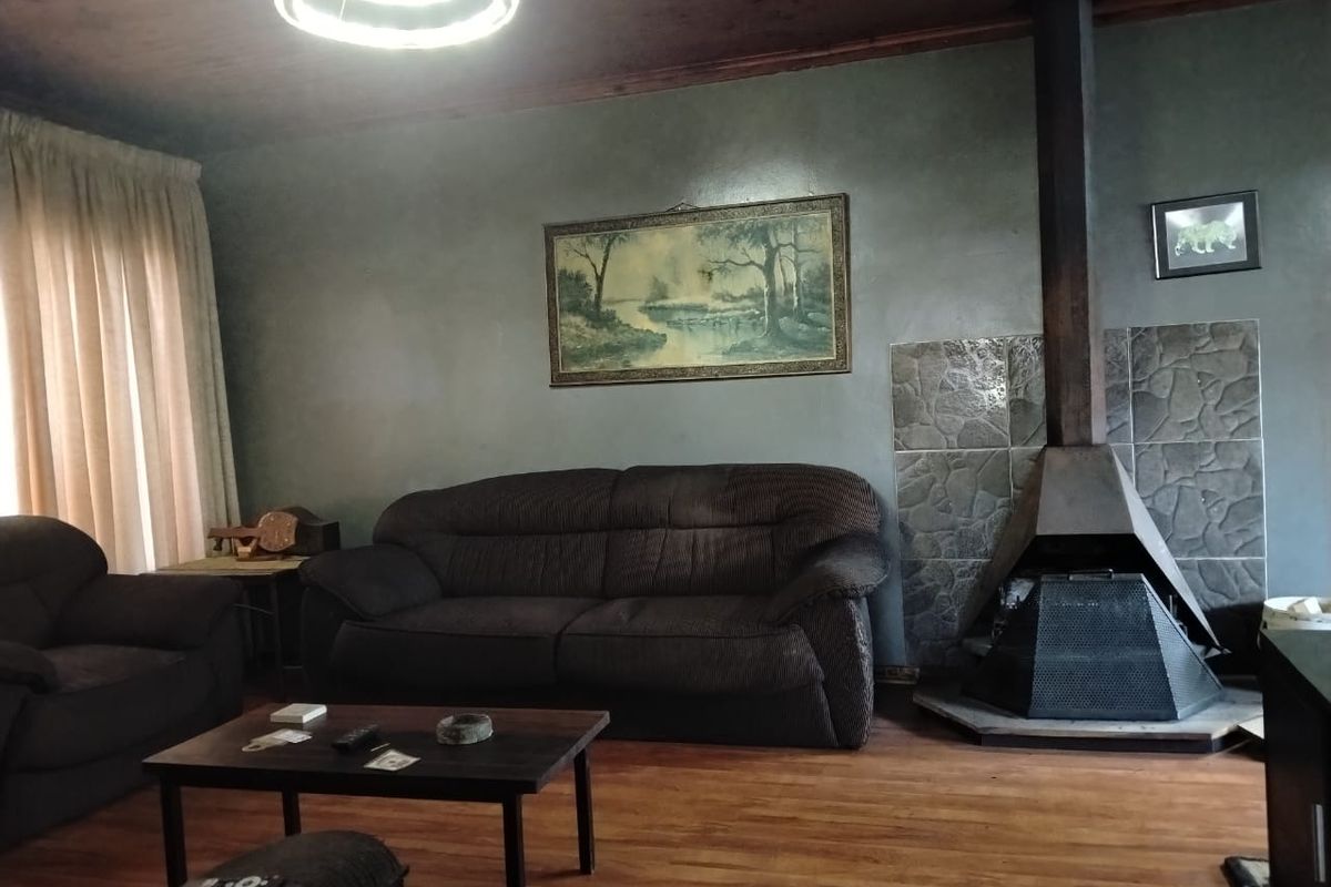 Living room featuring a prominent freestanding fireplace with stone surround, timber ceiling, and laminate flooring.