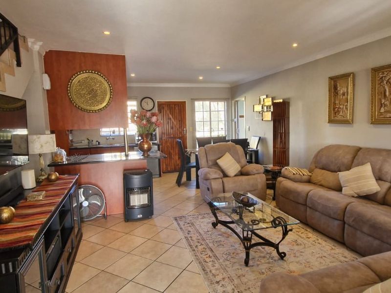 Open-plan living and kitchen area featuring tiled flooring, recessed lighting, and a staircase with a wrought iron balustrade.