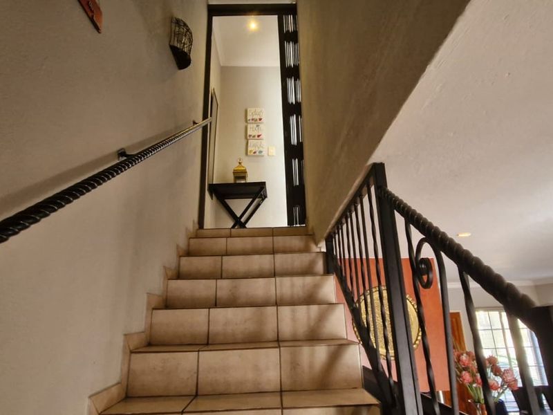 A staircase featuring tiled steps and a decorative wrought iron balustrade leading to an upper landing area.