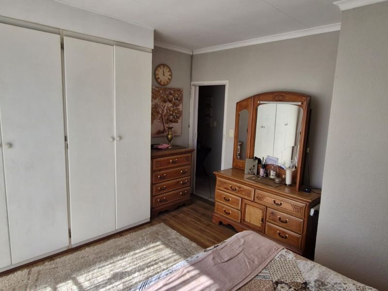A bedroom featuring built-in cupboards and laminate flooring, offering a functional space with neutral wall tones.