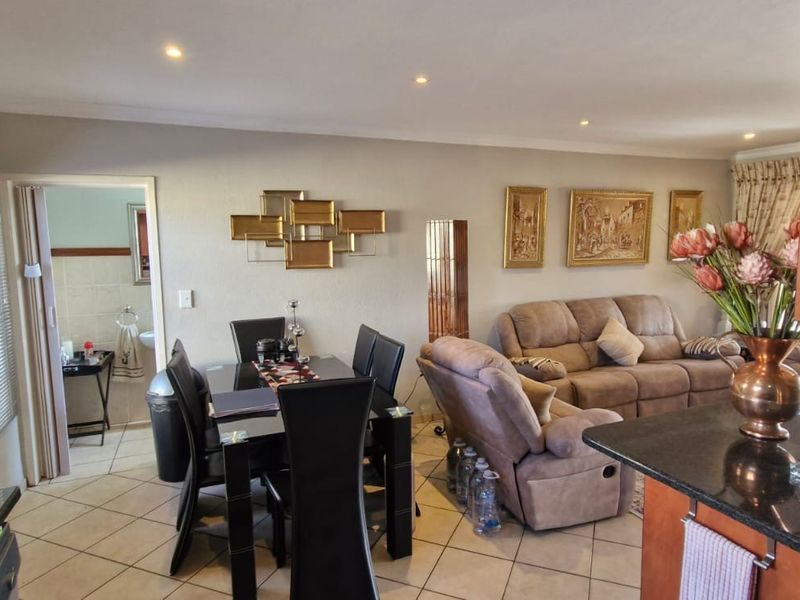 Open-plan living and dining area featuring ceramic floor tiles, recessed lighting, and a granite kitchen countertop, with direct access to an adjacent bathroom.
