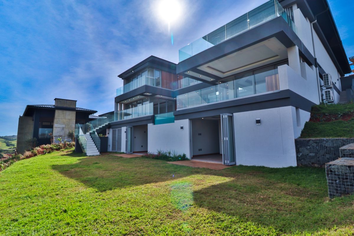 Modern multi-level residence featuring expansive glass balconies, bi-fold doors opening to the garden, and contemporary architectural finishes.