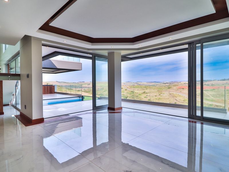 Spacious, modern living area featuring high-gloss floor tiles, recessed ceiling detail, and expansive sliding glass doors opening to a scenic outdoor terrace.