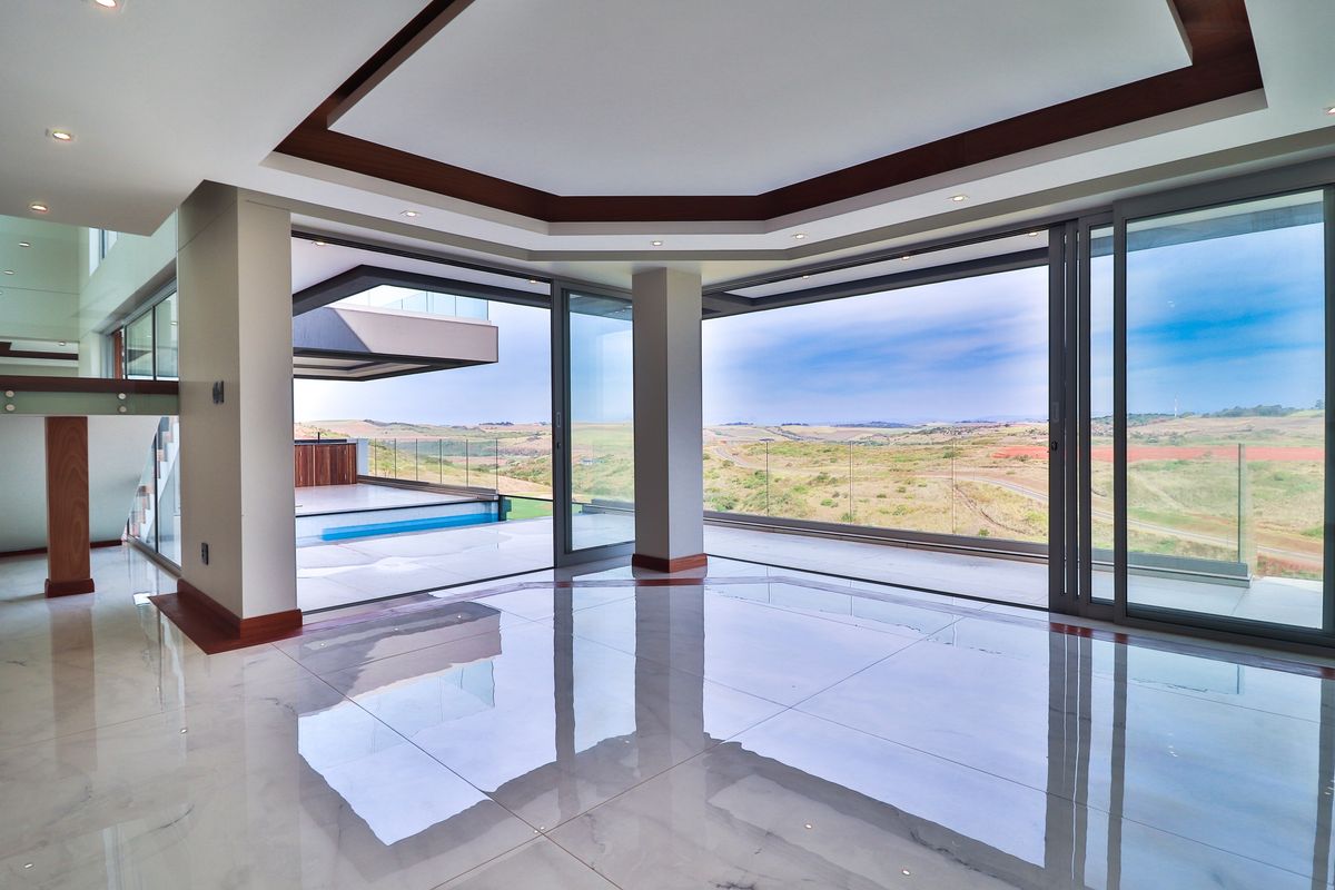 Spacious, modern living area featuring high-gloss floor tiles, recessed ceiling detail, and expansive sliding glass doors opening to a scenic outdoor terrace.