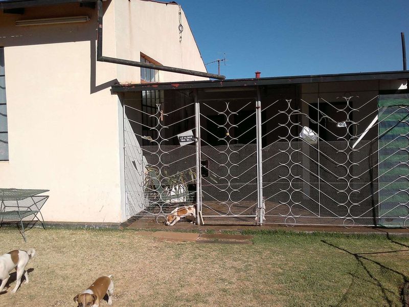 Rear exterior view of the farm building featuring a covered patio area enclosed by a decorative metal security gate.