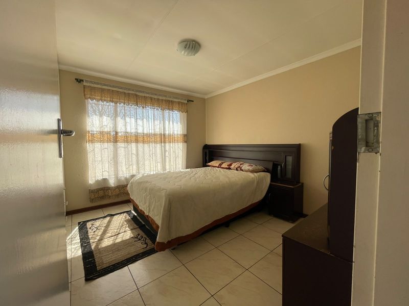 A standard bedroom featuring tiled flooring, neutral wall finishes, and a window with natural light.