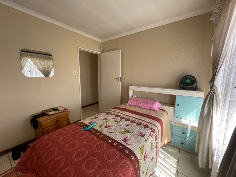 A functional bedroom featuring tiled flooring and a built-in headboard with integrated storage cabinetry.
