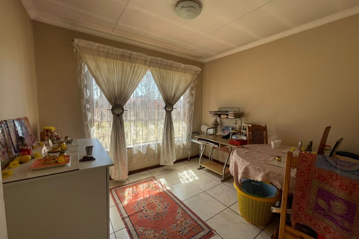 A functional living area featuring tiled flooring, a large window allowing natural light, and a standard ceiling light fixture.