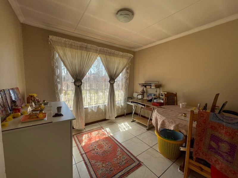 A functional living area featuring tiled flooring, a large window allowing natural light, and a standard ceiling light fixture.