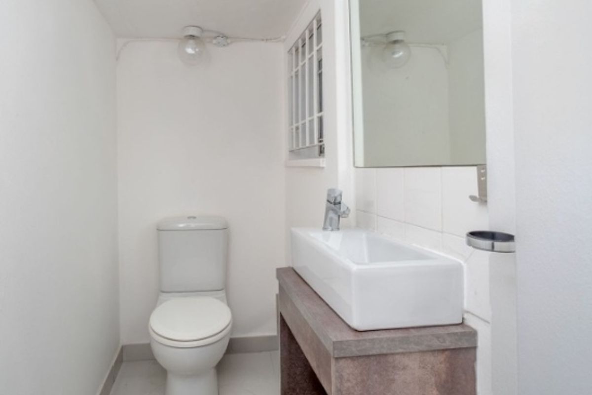 A compact, clean bathroom featuring a modern vessel basin on a vanity, a toilet, and a wall-mounted mirror.