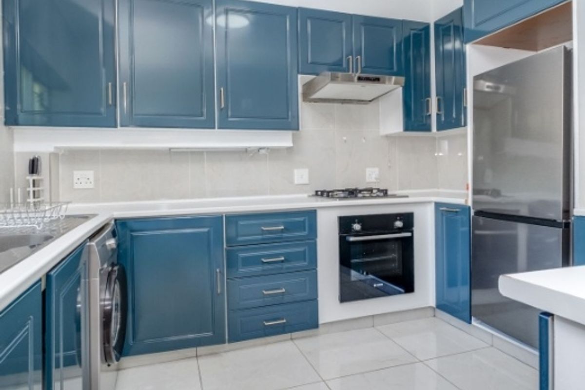 Modern kitchen featuring blue cabinetry, tiled flooring, built-in oven, gas hob, extractor fan, and integrated laundry appliance.