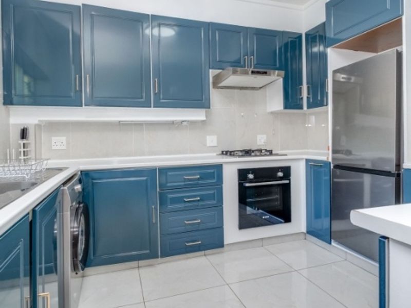 Modern kitchen featuring blue cabinetry, tiled flooring, built-in oven, gas hob, extractor fan, and integrated laundry appliance.
