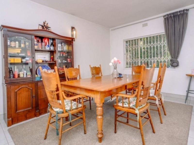 A dining room featuring tiled flooring and a window fitted with a security gate, providing a functional space for family meals.