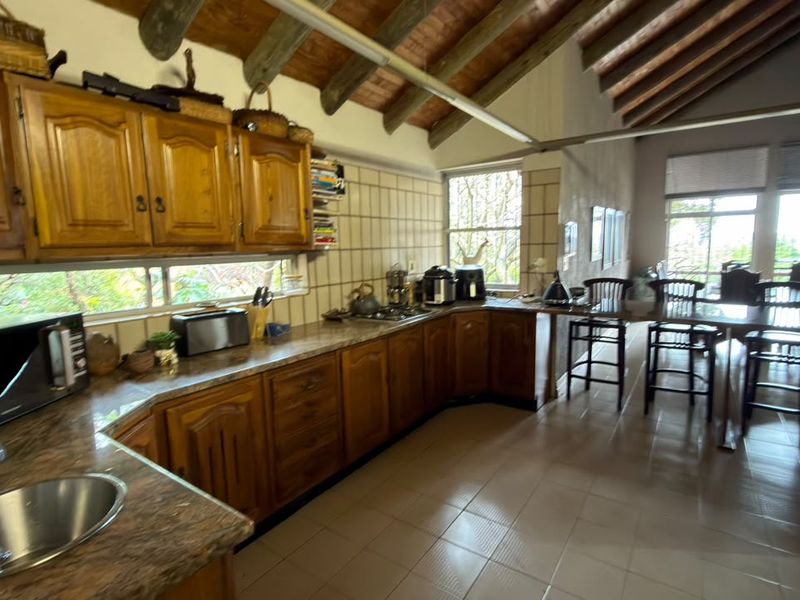 Spacious open-plan kitchen featuring traditional wooden cabinetry, tiled flooring, and exposed timber ceiling beams, offering a functional layout with ample counter space.