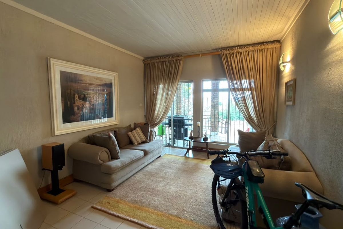 A comfortable living room featuring tiled floors, a timber panelled ceiling, and sliding glass doors that provide access to the outdoor area.