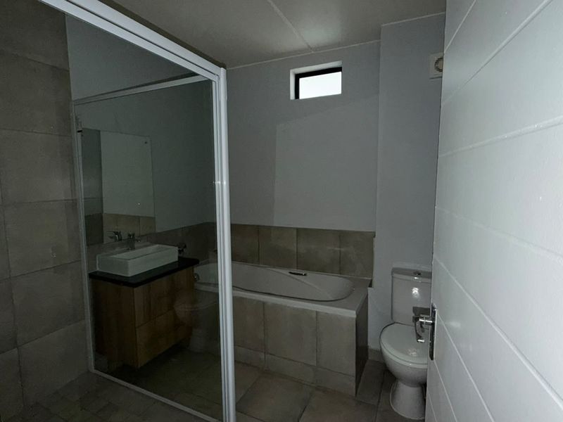 A clean, modern bathroom featuring a built-in vanity with a vessel sink, a bathtub, a separate shower enclosure, and a toilet.