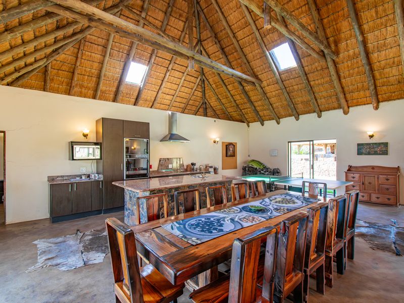 Spacious open-plan living and kitchen area featuring a high vaulted thatched ceiling with exposed timber trusses, skylights, and a central granite-topped kitchen island.