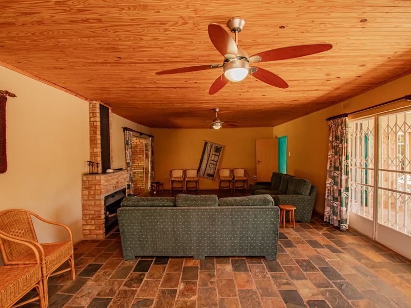 Spacious living room featuring a brick fireplace, natural slate tile flooring, and a warm timber-clad ceiling with integrated fans.