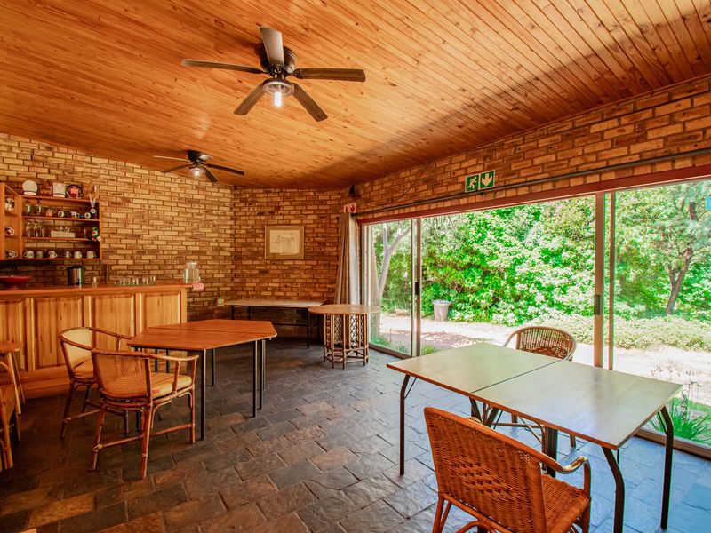 Spacious bar area featuring exposed brick walls, timber ceiling, slate flooring, and large sliding glass doors opening to the garden.