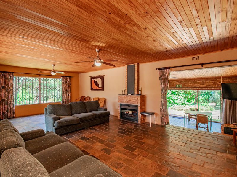Spacious living room featuring a timber ceiling, stone tile flooring, and a built-in brick fireplace, with direct access to an outdoor patio area.