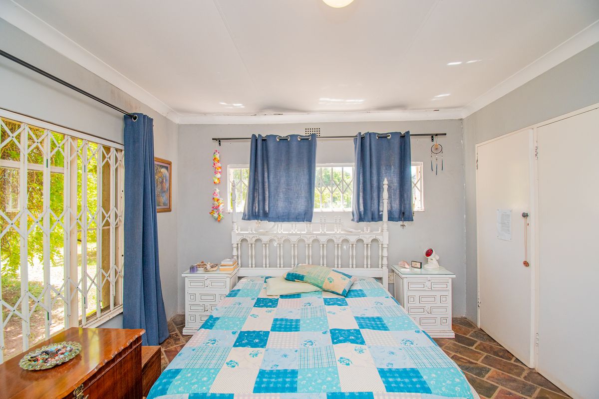A bedroom featuring stone tile flooring, a built-in cupboard, and a security gate leading to the exterior.