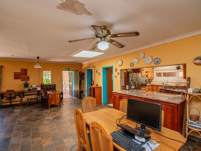 Open-plan living and kitchen area featuring stone tile flooring, a ceiling fan, and a kitchen with granite countertops and built-in appliances.