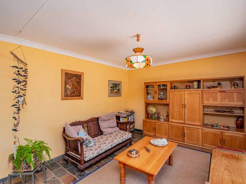 A living room featuring slate tile flooring, coved ceilings, and extensive built-in wooden cabinetry, offering a traditional farm-style aesthetic.