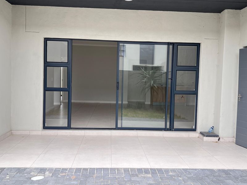 A clean, covered patio area featuring tiled flooring and large sliding glass doors providing access to the interior living space.