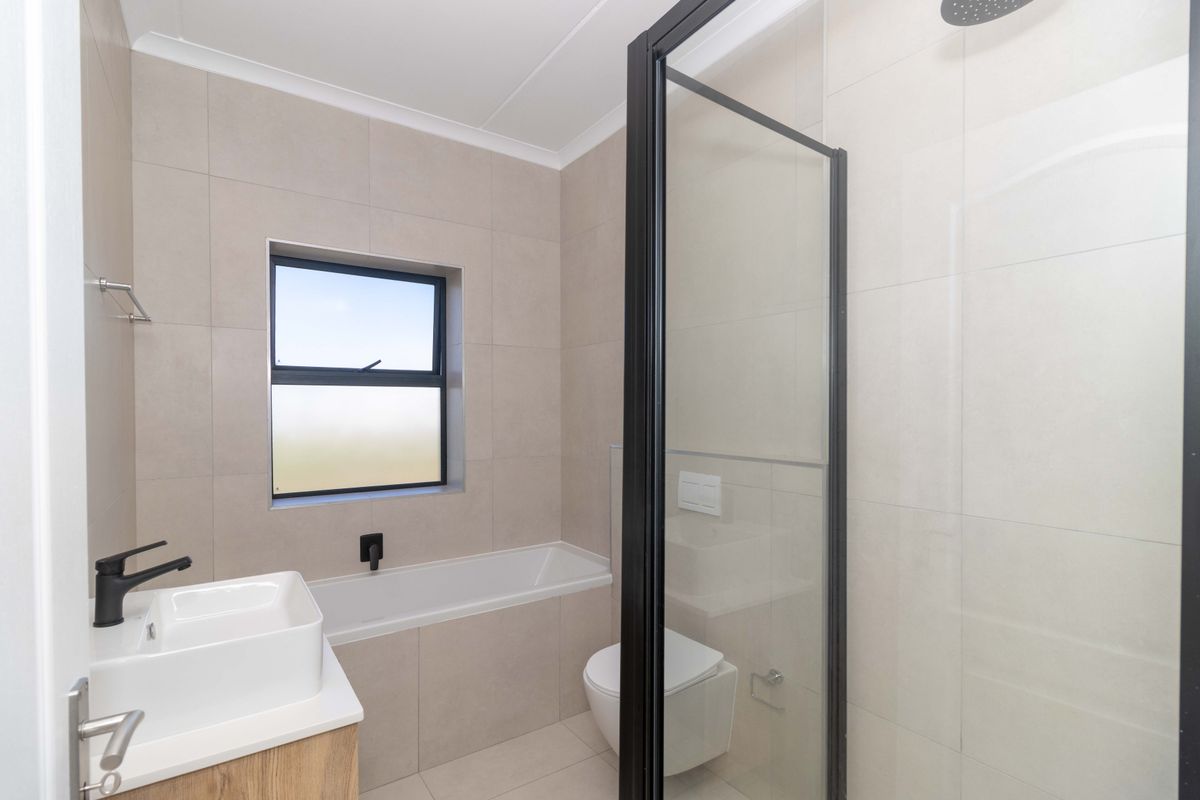 Modern bathroom featuring a built-in bathtub, separate shower enclosure with black frame, wall-mounted toilet, and a contemporary vanity basin with matte black fixtures.