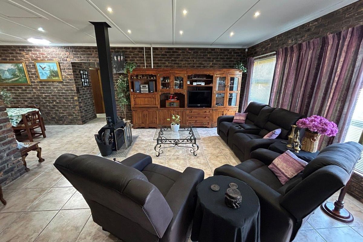 Spacious living room featuring exposed brick walls, tiled flooring, and a central freestanding fireplace, creating a warm and rustic atmosphere.