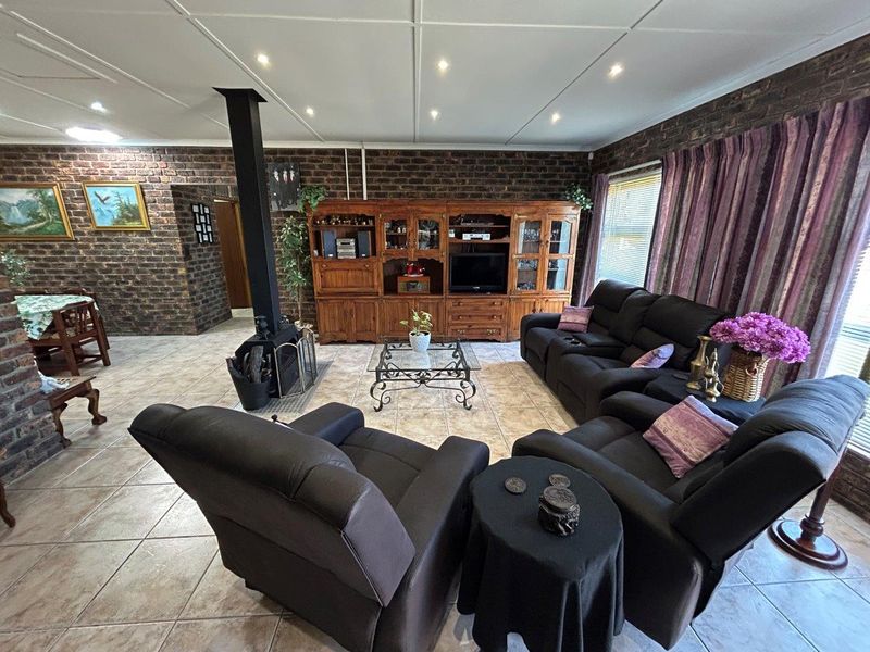 Spacious living room featuring exposed brick walls, tiled flooring, and a central freestanding fireplace, creating a warm and rustic atmosphere.