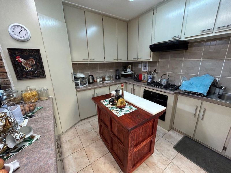 Functional kitchen featuring laminate cabinetry, tiled backsplash, built-in oven with gas hob, and a central wooden island unit.