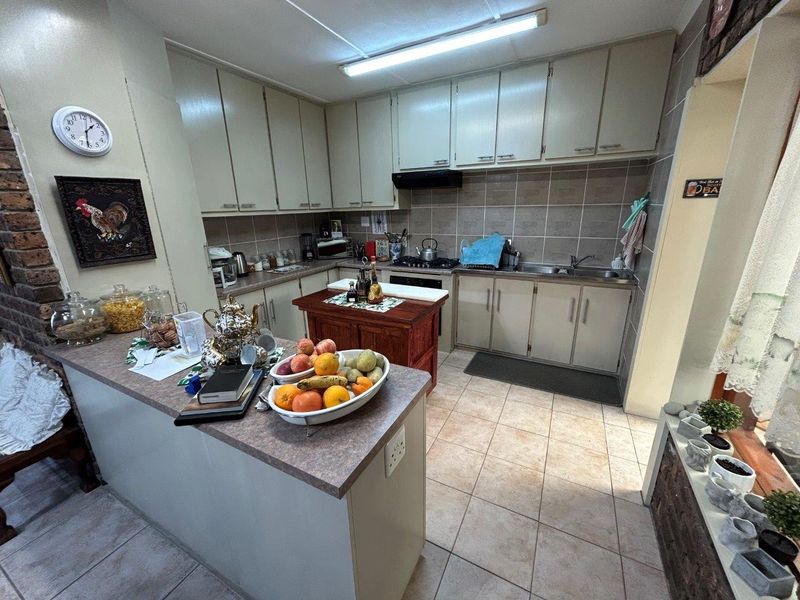 A functional kitchen featuring ample built-in cabinetry, laminate countertops, a double bowl sink, and tiled flooring with a practical layout.