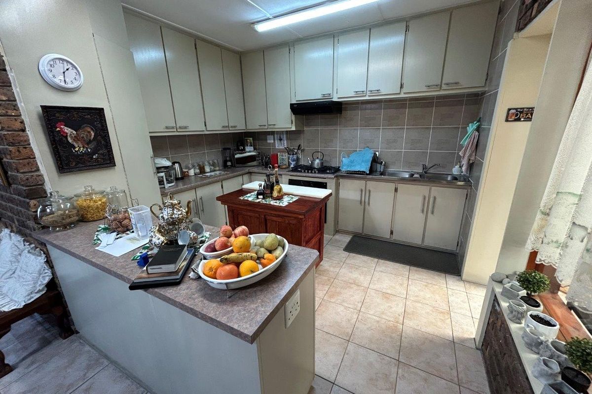 A functional kitchen featuring ample built-in cabinetry, laminate countertops, a double bowl sink, and tiled flooring with a practical layout.