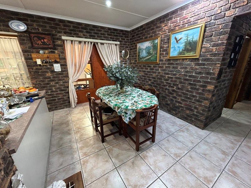 Dining area featuring rustic exposed brick walls and neutral ceramic floor tiles, with direct access to the exterior through a sliding glass door.