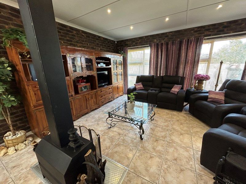 A living room featuring exposed brick walls, tiled flooring, and a prominent freestanding fireplace, offering a cozy and rustic atmosphere.