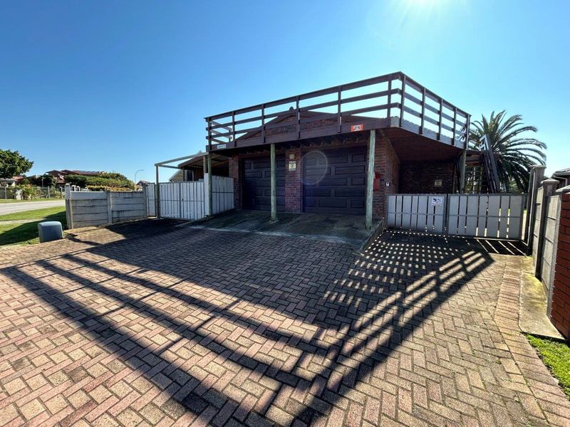 Front view of a double garage with a paved driveway and an elevated balcony featuring timber railings.
