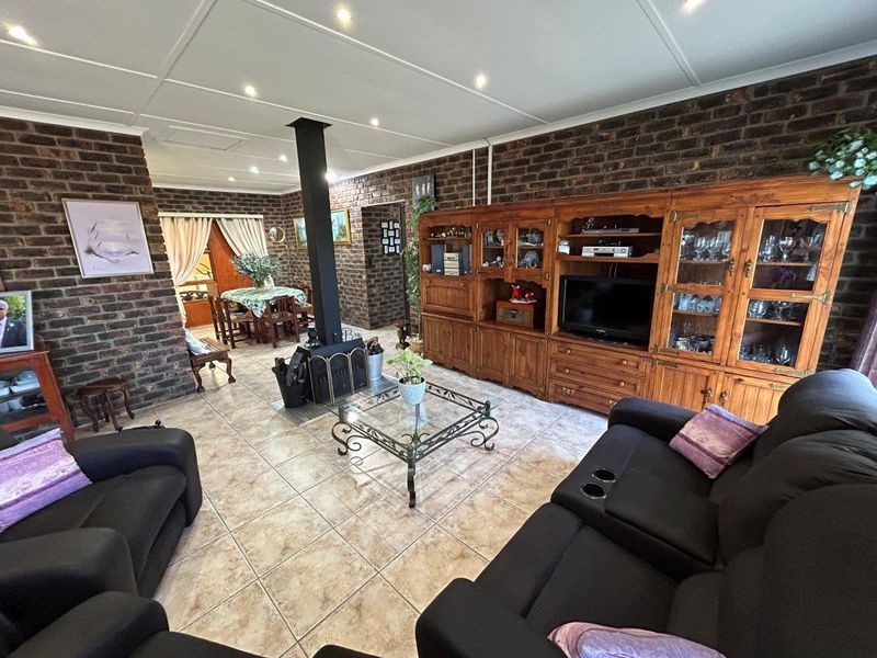 Spacious open-plan living area featuring exposed brick walls, tiled flooring, and a central freestanding fireplace, creating a warm and rustic atmosphere.
